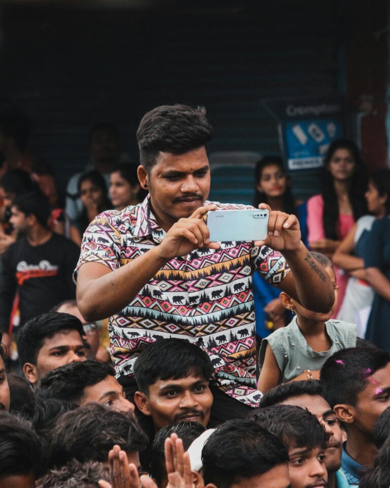 A vibrant crowd in Nagothane, India, captures moments on a smartphone.