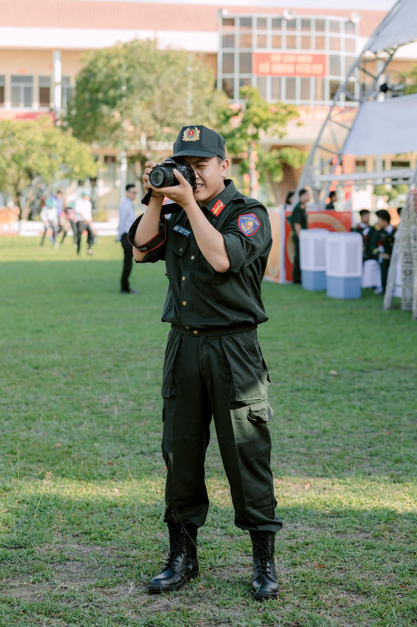 A young male police officer captures moments with a camera during a community event.