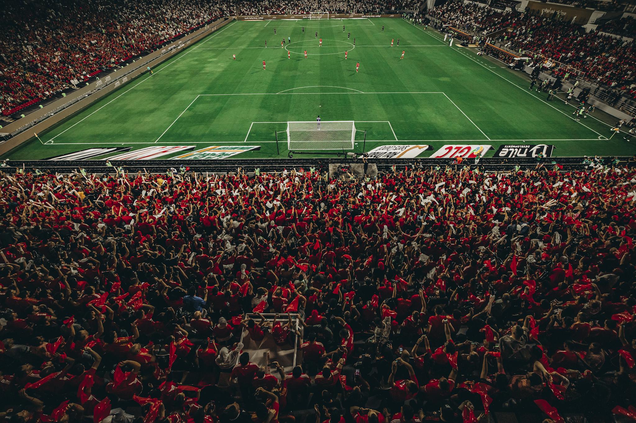 Aerial shot of a lively football match with enthusiastic fans in a packed stadium.