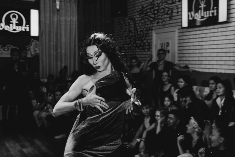 Captivating black and white photo of a drag queen performing for an audience in a nightclub.
