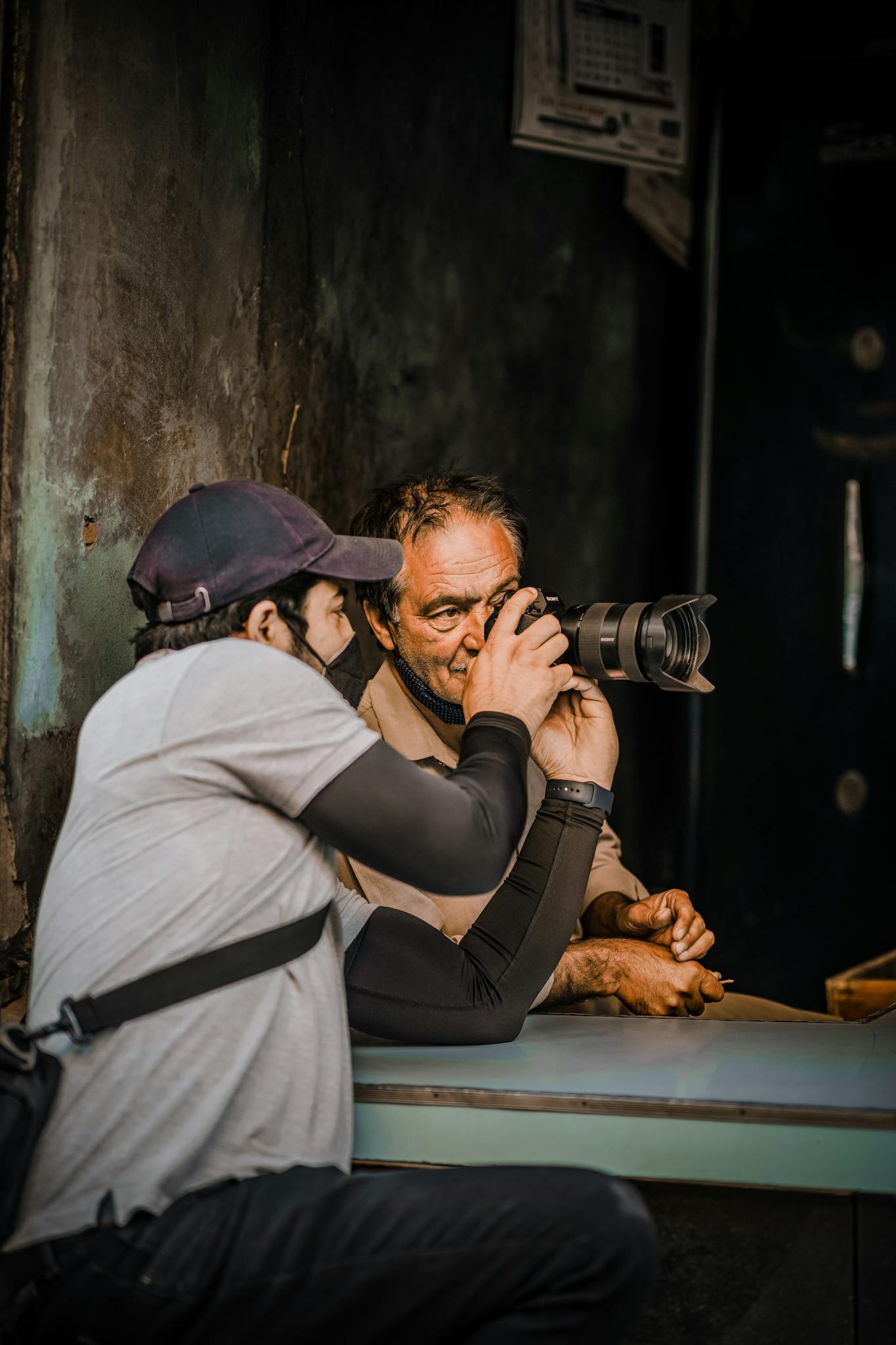 Elderly man learns photography technique from a skilled photographer.